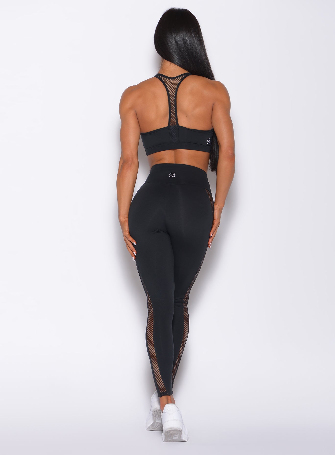 Back profile view of a model in our black Mohawk leggings and a matching bra