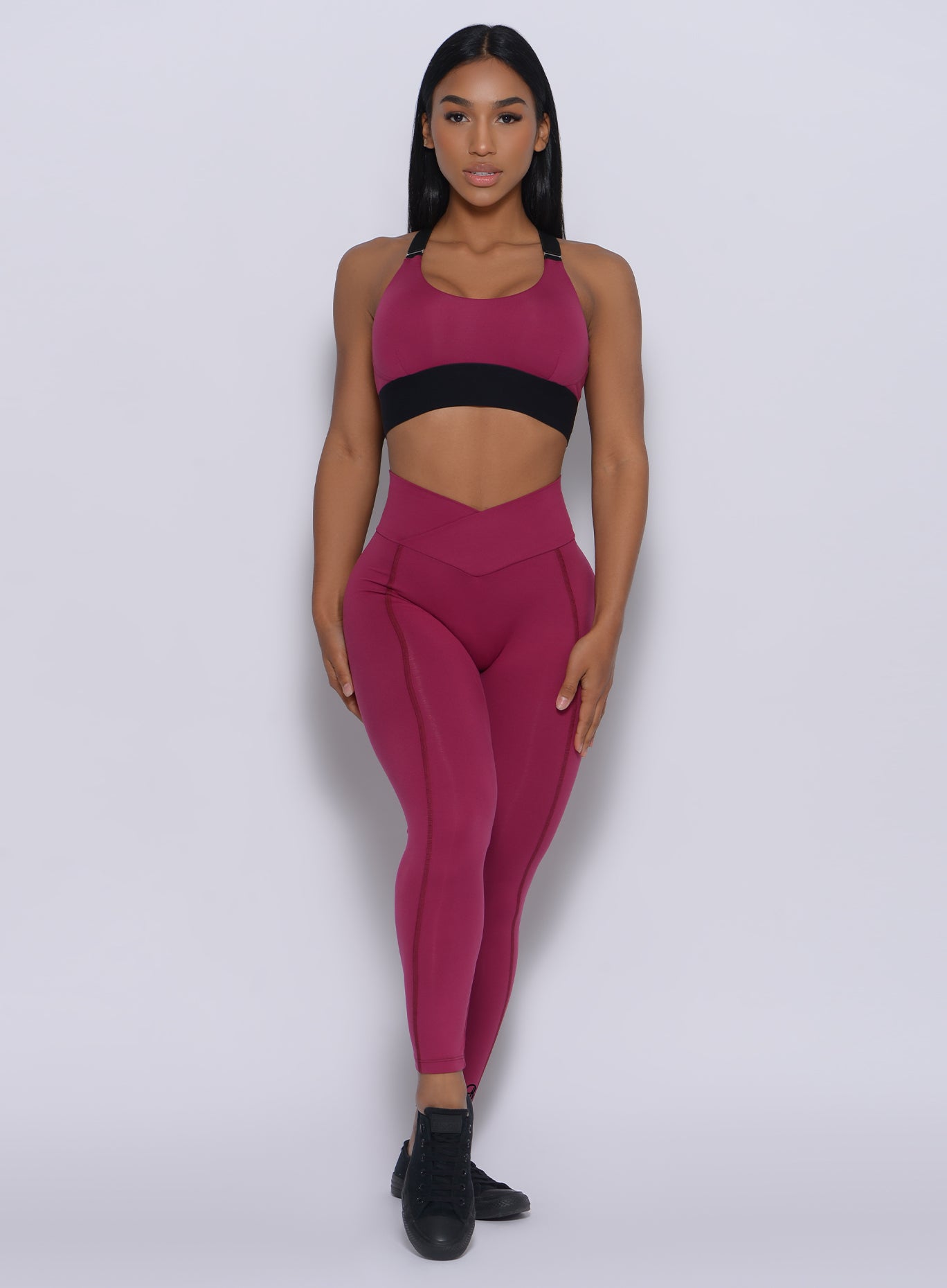 Front profile view of the model in our Brazilian leggings in mulberry color and a matching bra