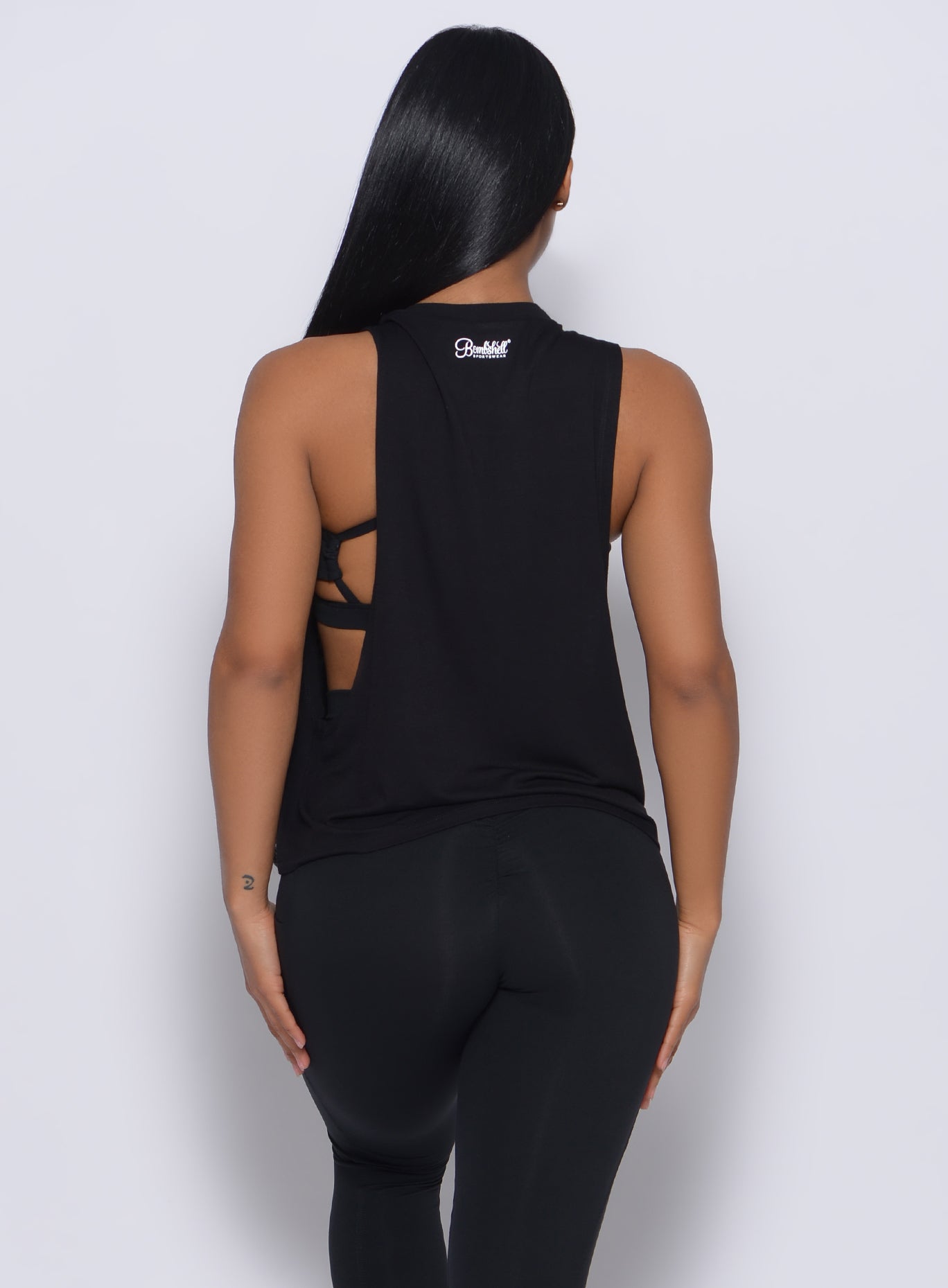 Back profile view of a model in our black muscle tank and a matching leggings