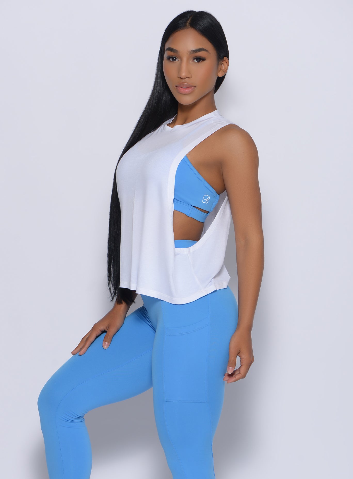 Left side view of a model in our white muscle tank and a blue leggings