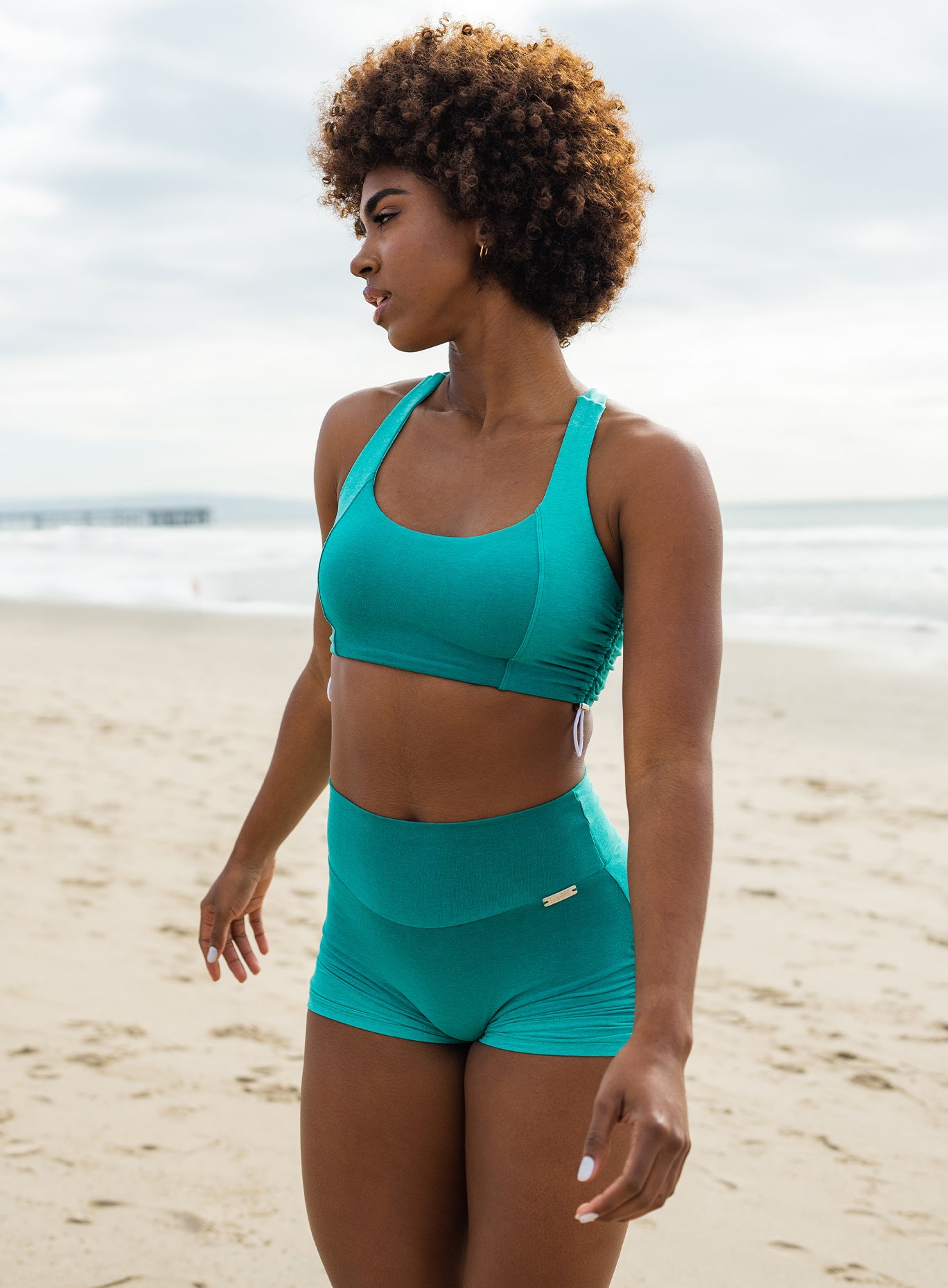 Front side profile view of a model in our toggle sports bra in Ombre Ibiza Green and a matching shorts