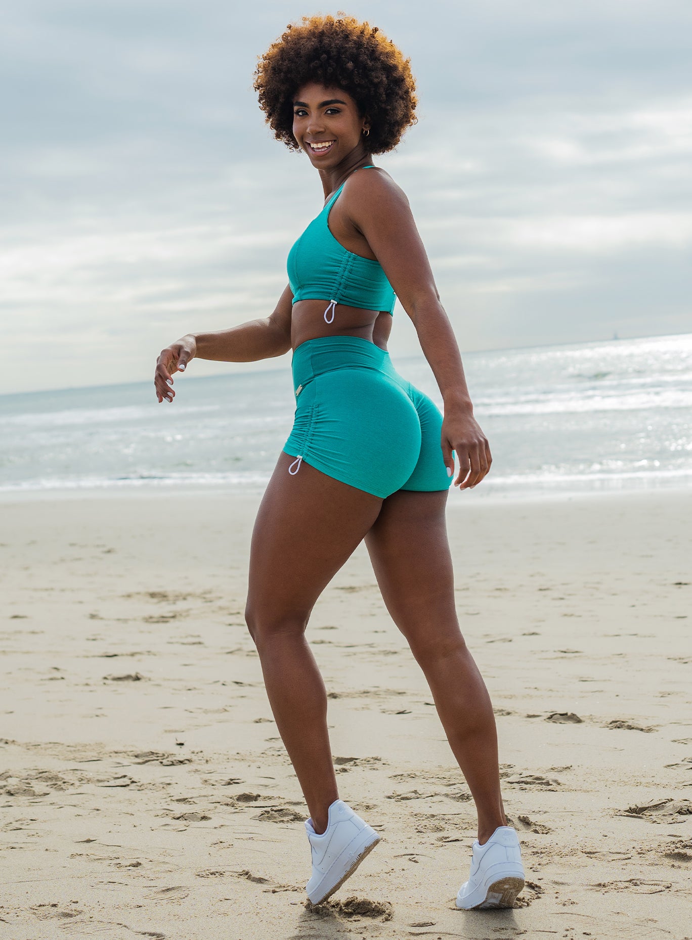 Left side profile picture of a model in our toggle shorts in Ombre Ibiza Green and a matching bra