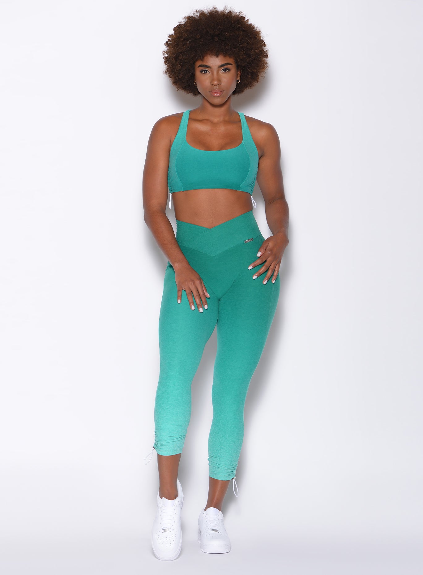 Front profile view of a model wearing our toggle leggings in Ombre Ibiza Green and a matching bra
