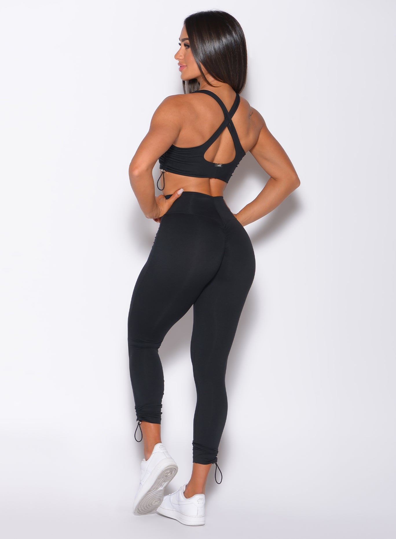 Back profile view of a model in our black toggle leggings and a matching sports bra 