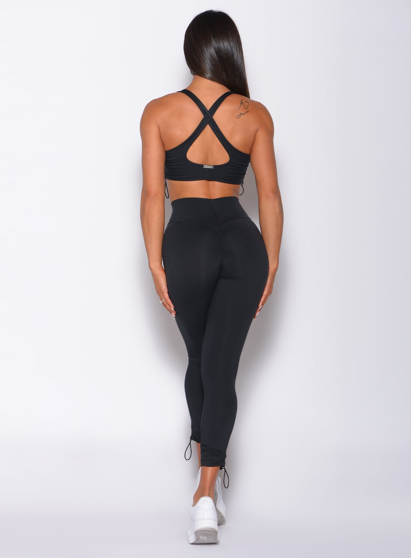 Back profile view of a model wearing our black toggle leggings and a matching sports bra 