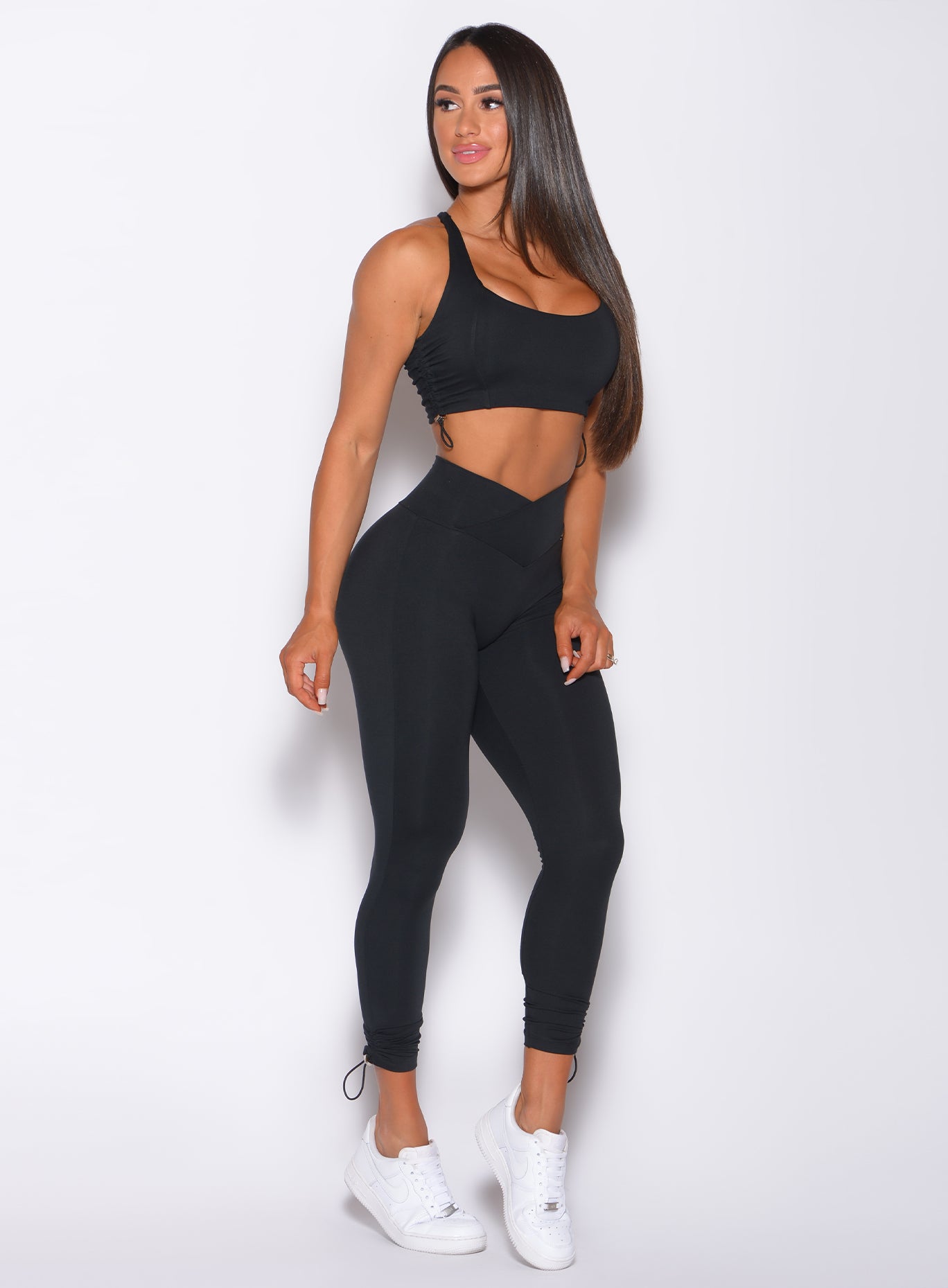 Right side profile view of a model angled slightly to her right  wearing our black toggle leggings and a sports bra 