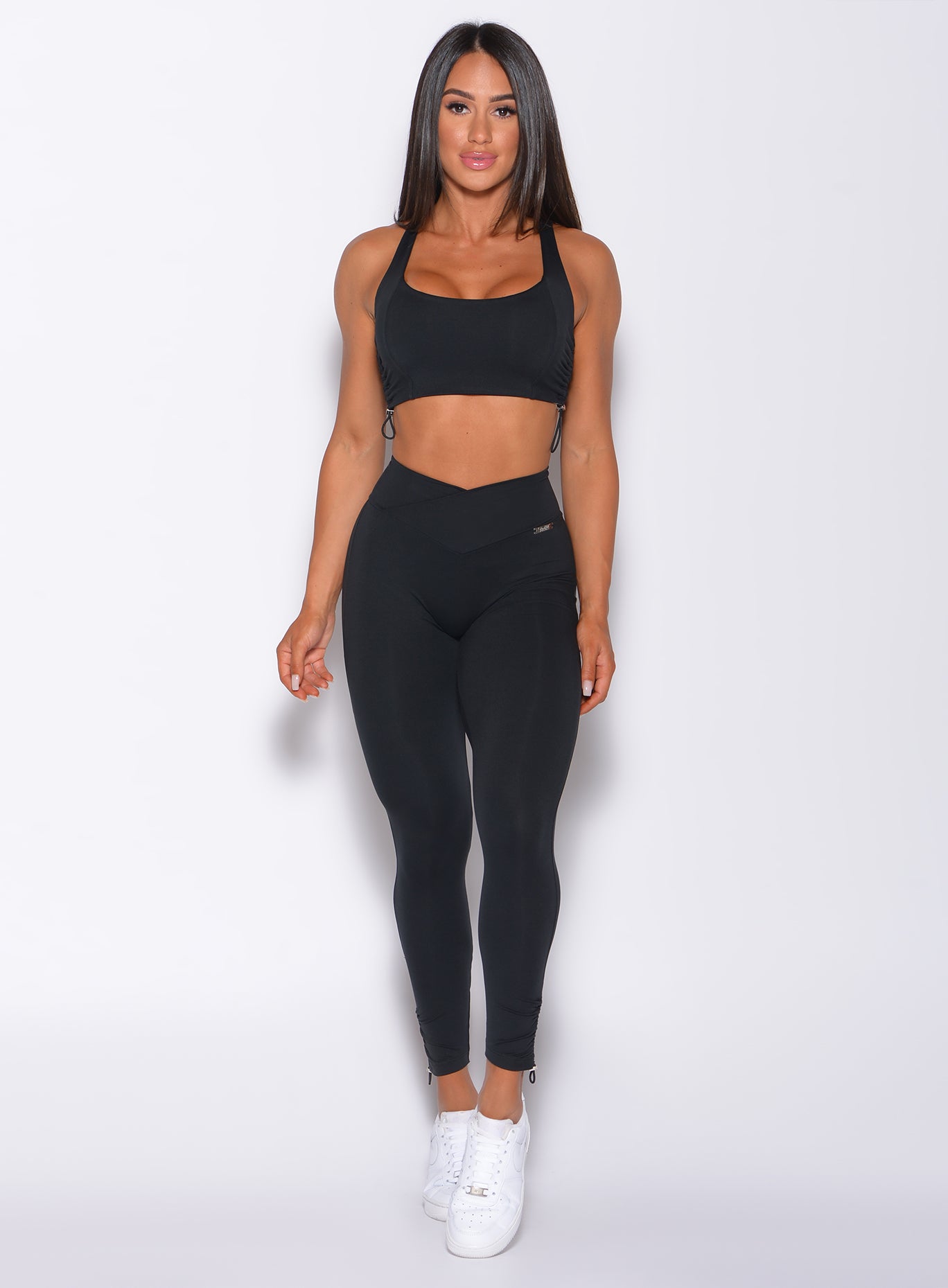 Model facing forward wearing our black toggle leggings and a matching sports bra 