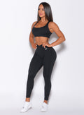 Left side profile view of a model angled slightly to her left wearing our black toggle leggings and a matching bra 
