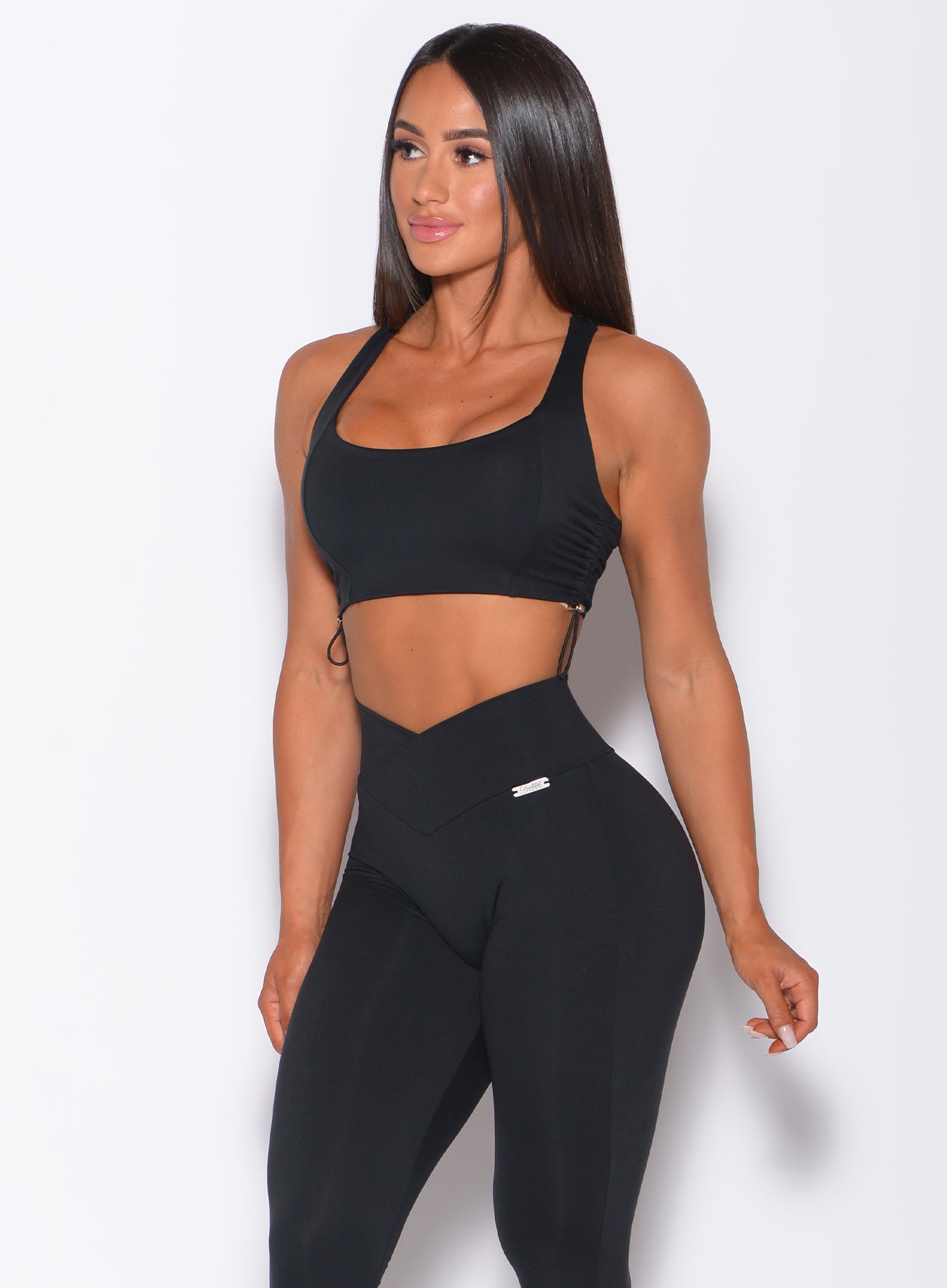 Front profile view of a model in our black toggle sports bra and a matching mid rise leggings