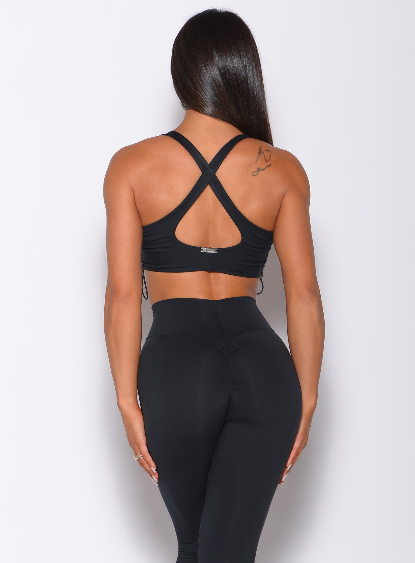 back view of a model of a model in our black toggle sports bra and a matching black leggings