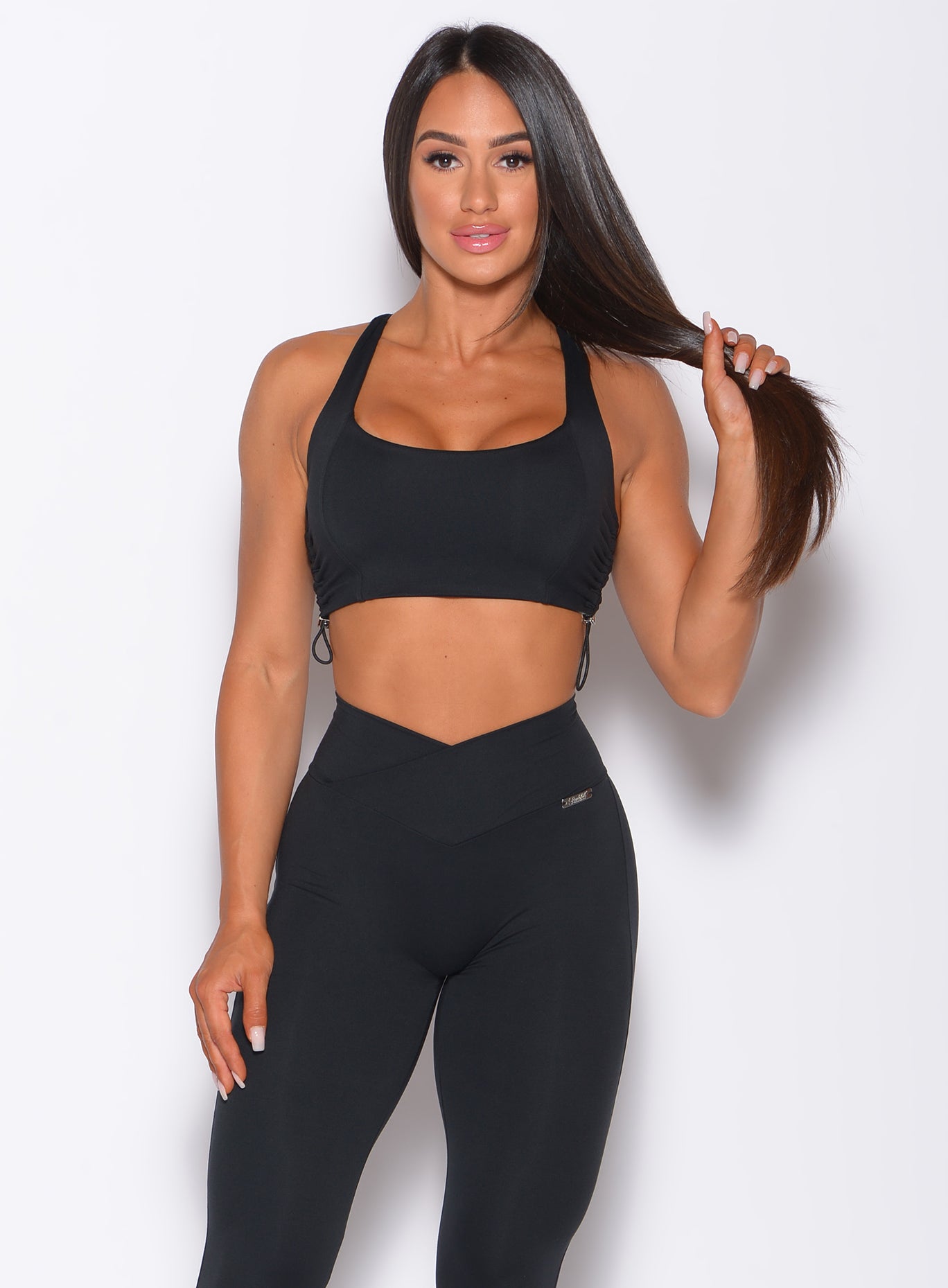 Front side view of a model in our black toggle sports bra and a matching leggings 