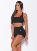 Front profile view of a model wearing our black toggle sports bra and a matching mid rise shorts