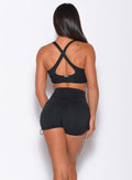 Back profile view of a model wearing our toggle sports bra in black along with a matching toggle shorts 