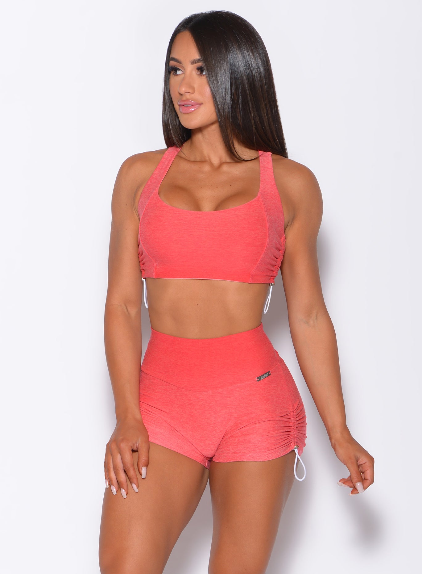 Front profile view of a model in our toggle sports bra in Ombre Fiji Coral and a matching Shorts