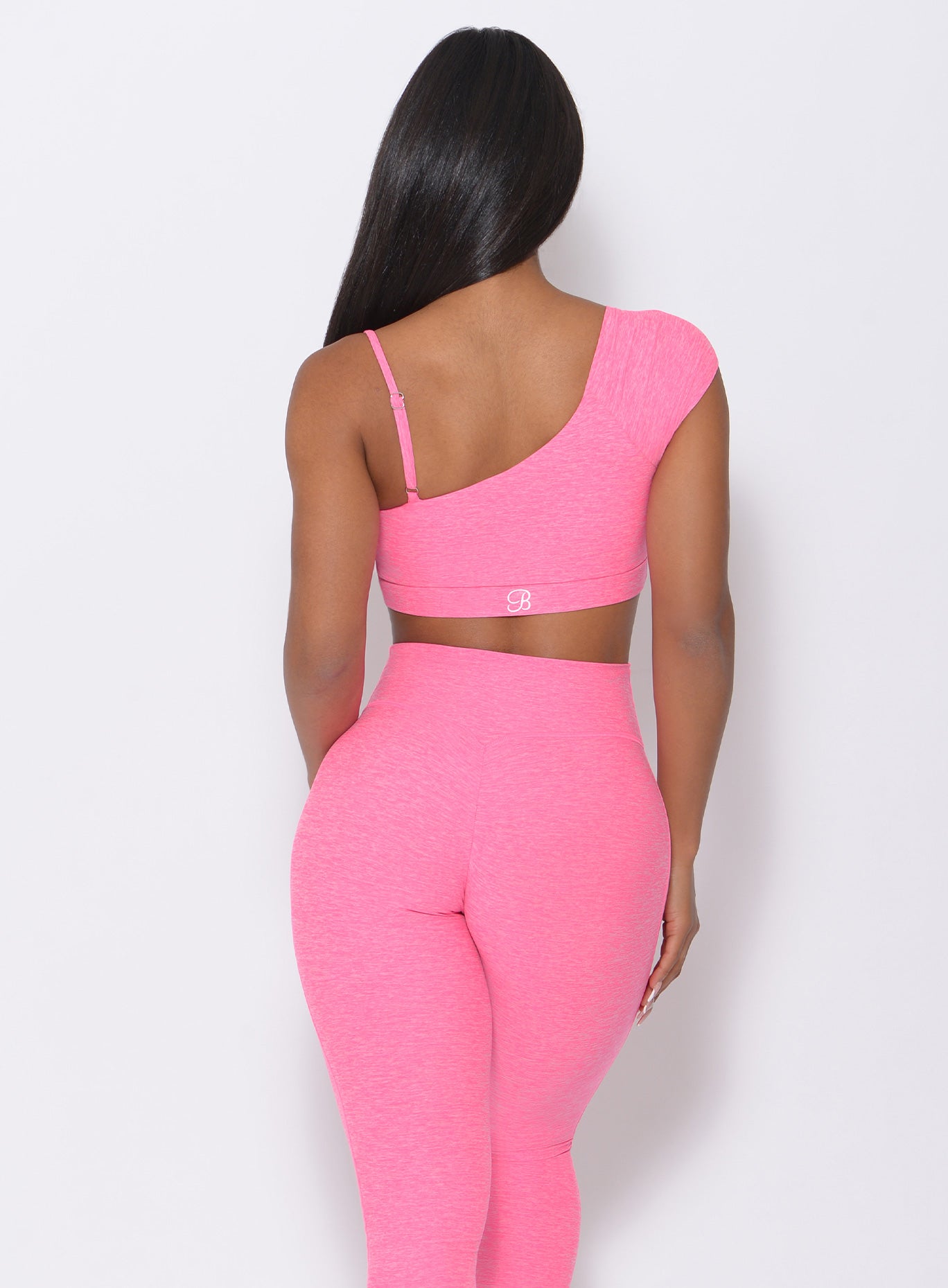 Back view of the model in our Adore Sports Bra in pink and a matching leggings