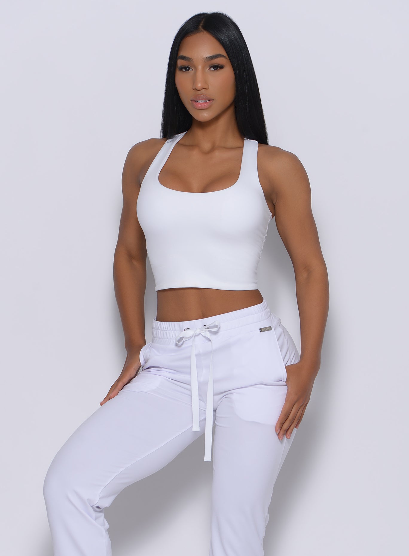 Front profile view of a model in our white elevated tank bra and a matching joggers 