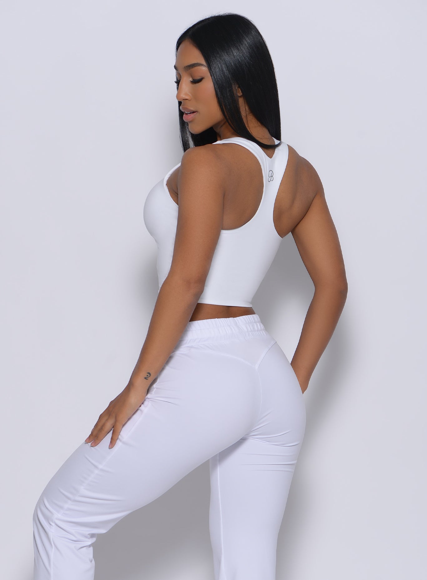 Left side  profile view of a model in our white elevated tank bra and a matching joggers