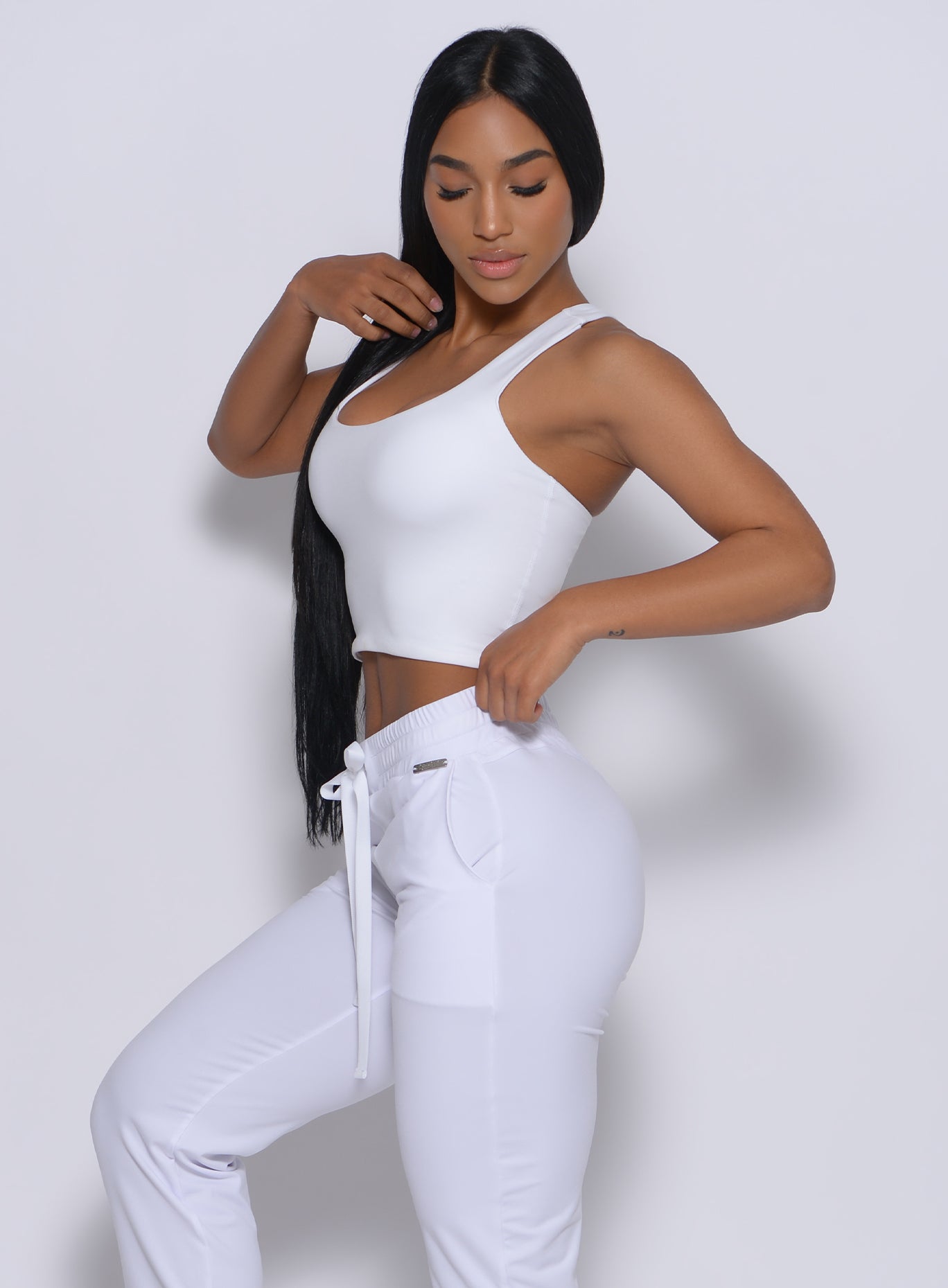 Right side  profile view of a model wearing our white elevated tank bra and a matching joggers