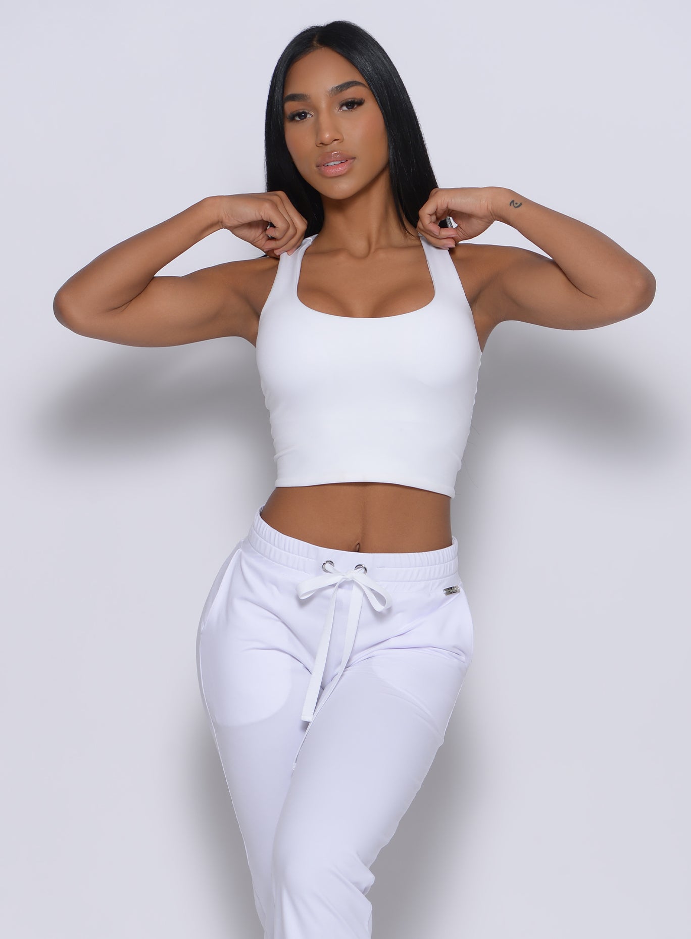 Front  profile view of a model wearing our white elevated tank bra and a matching joggers