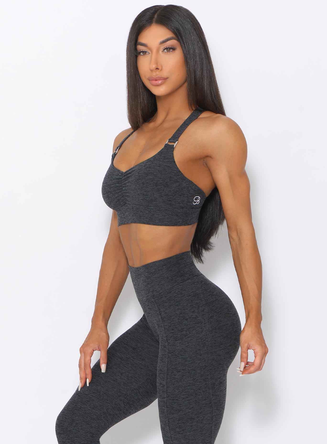 Left side view view of the model wearing our perfection sports bra in charcoal color and a matching high waist leggings