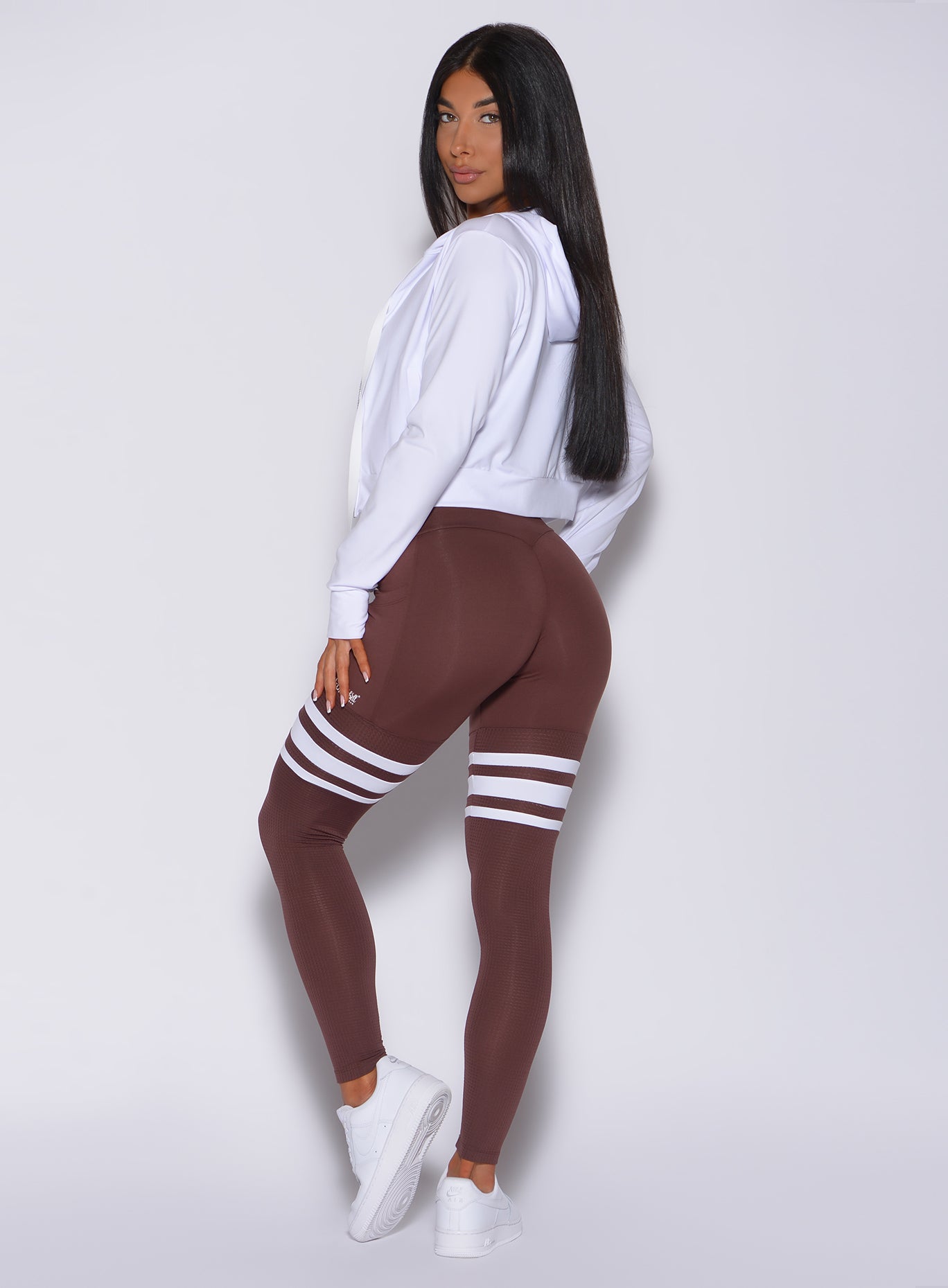Left side  profile view of a model in our perform thigh high in chocolate color and a white hoodie