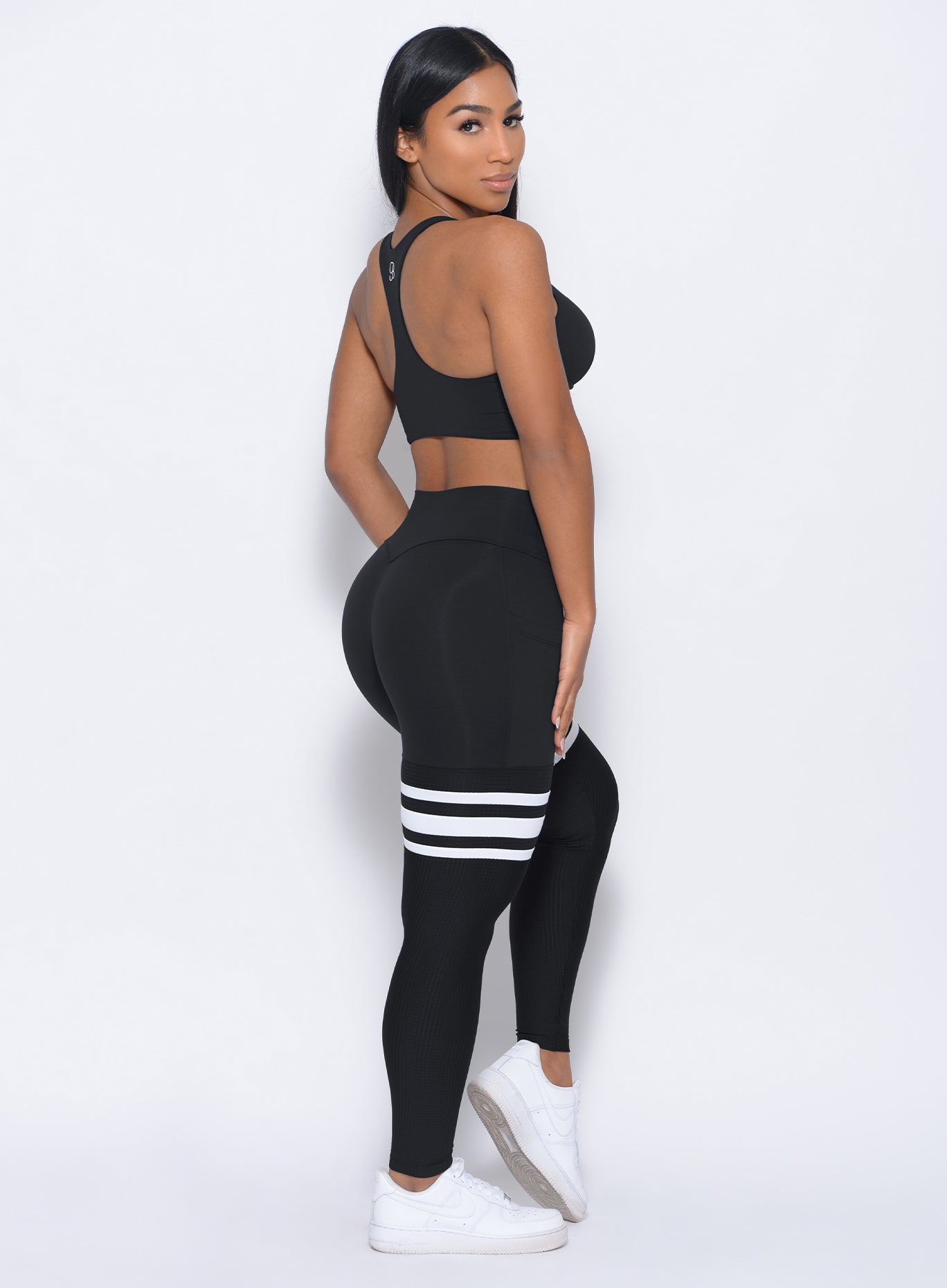 Right side profile view of the model wearing our black perform thigh high leggings and a matching bralette 