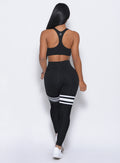 Back profile view of a model wearing our  black perform thigh high leggings and a matching top 