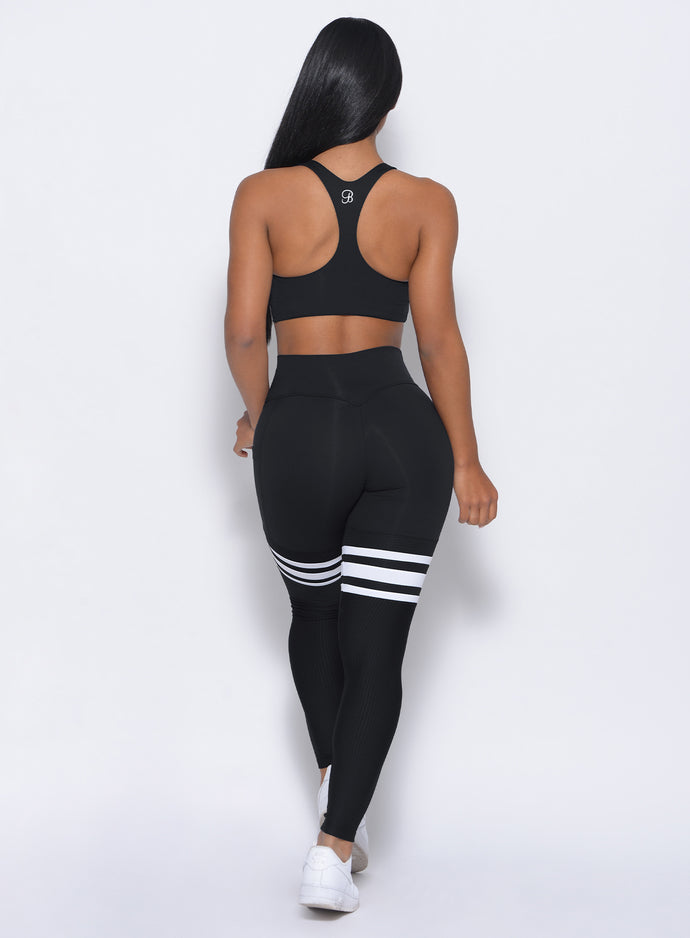 Back profile view of a model wearing our  black perform thigh high leggings and a matching top 