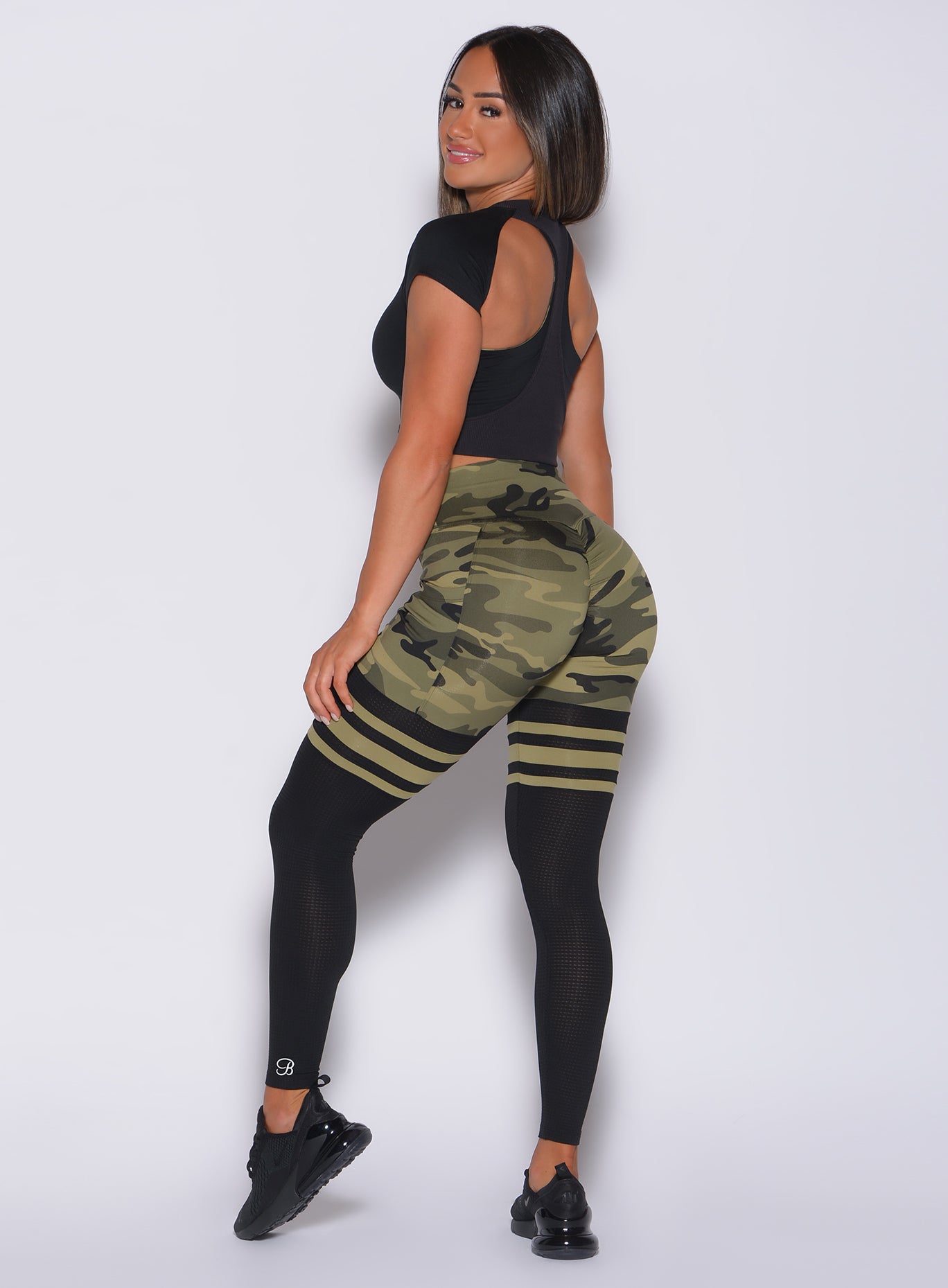 Left side profile view of a model in our green camo scrunch thigh high and a black bra tank 