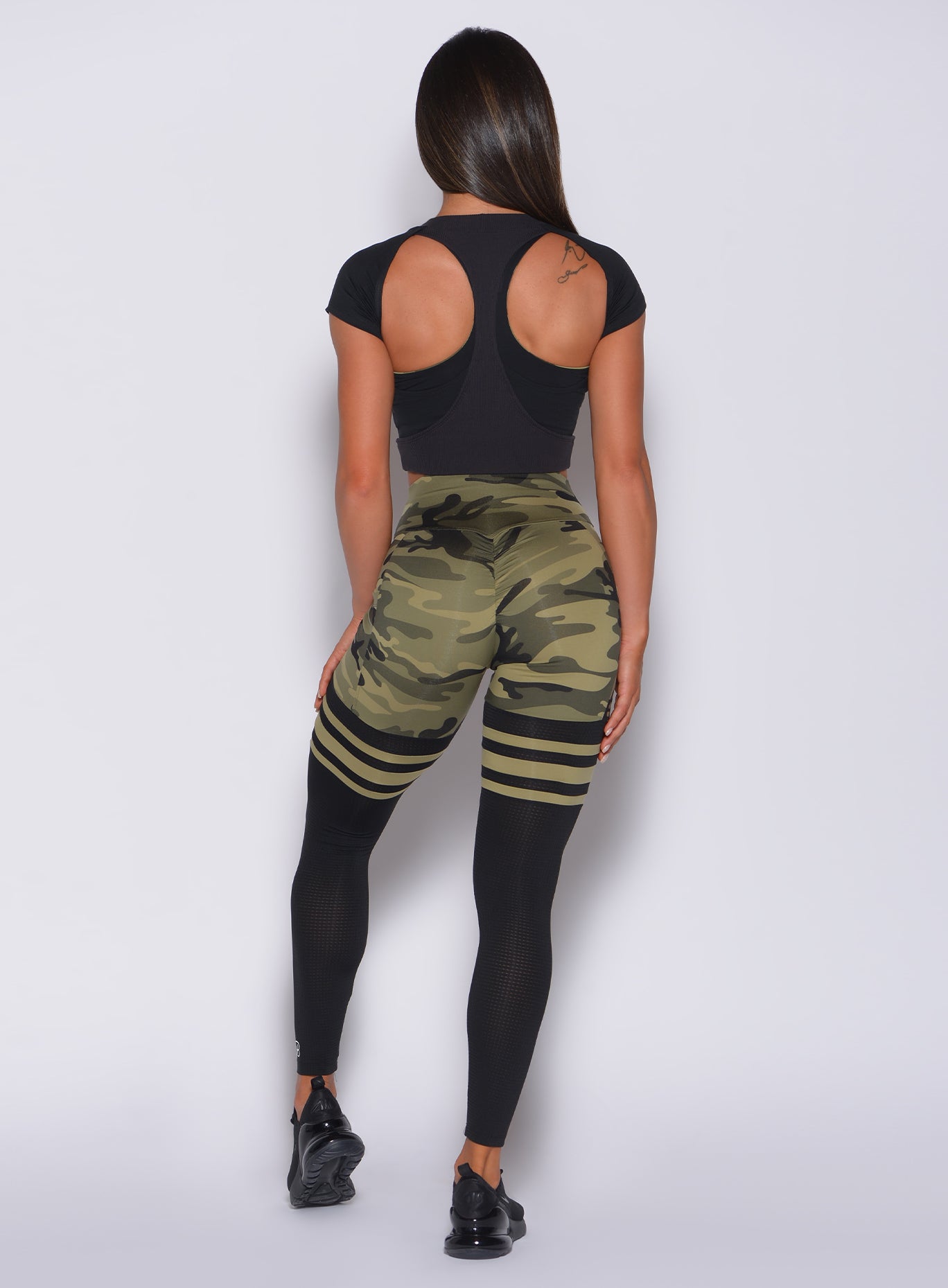 Back profile view of a model in our green camo scrunch thigh high and a black bra tank