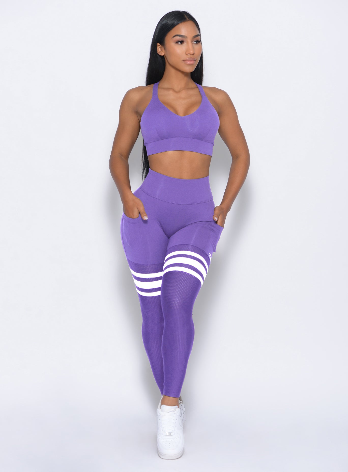 Front profile view of the model in our perform thigh highs in royal purple color and a matching bra