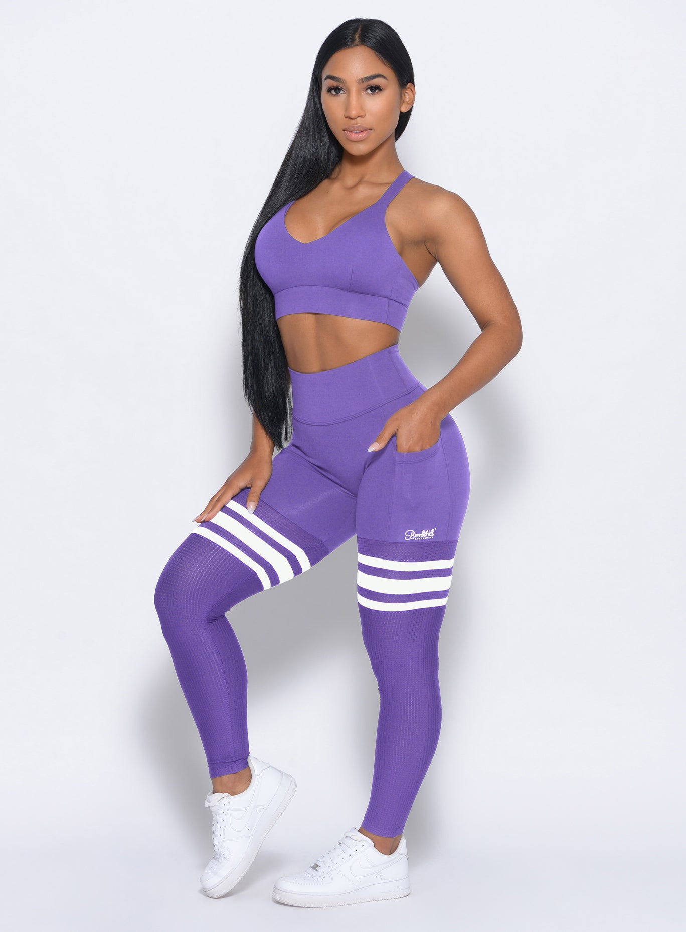 Model facing forward wearing our perform thigh highs in royal purple color with three white stripes on thighs and a matching bra