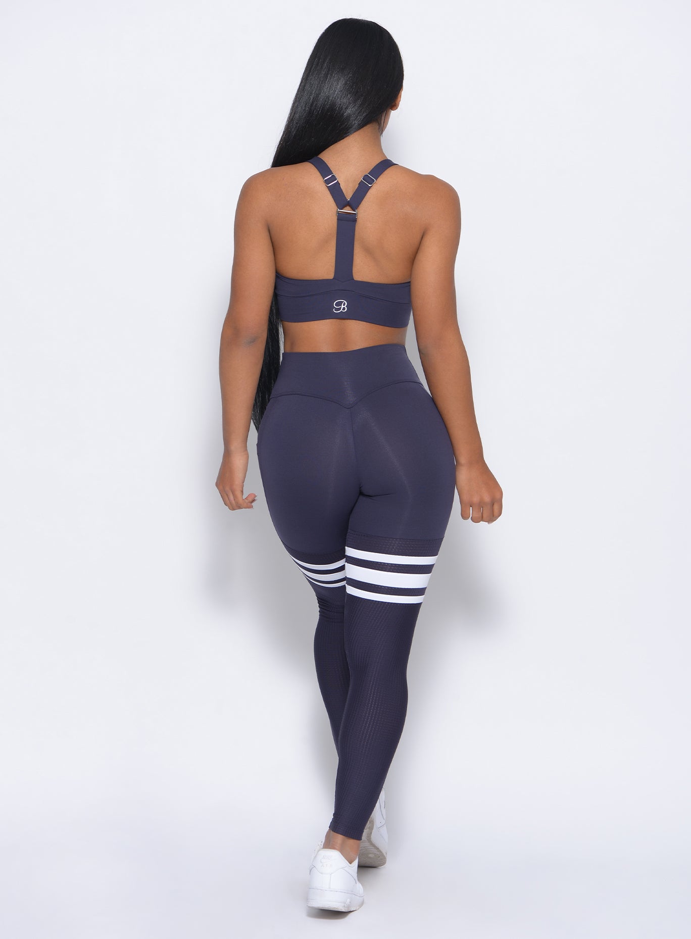 Back profile view of the model in our perform thigh highs in twilight blue color with white stripes and a matching bra