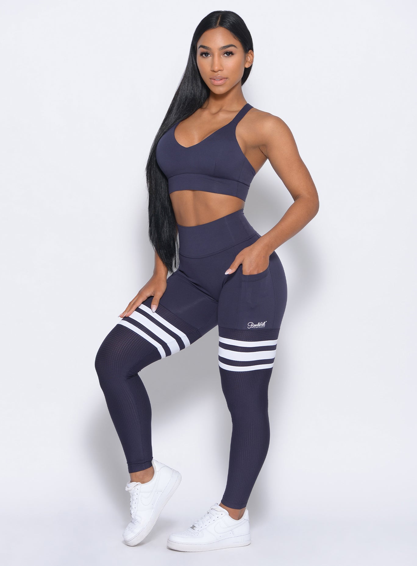 Left side view of the model angled left wearing our synergy sports bra in twilight blue color and a matching high waist leggings
