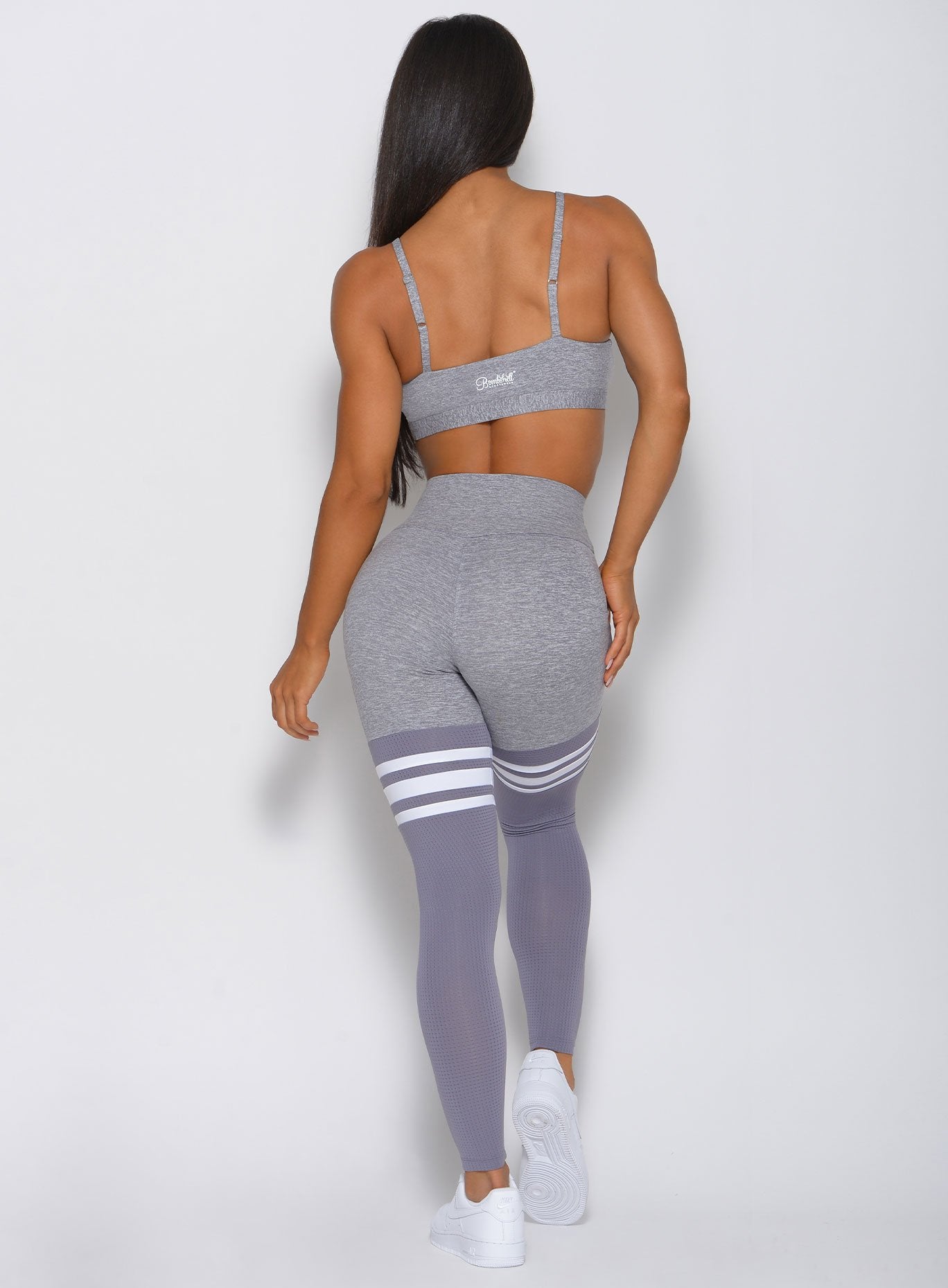 Model facing back wearing grey sports bra and matching high waist leggings