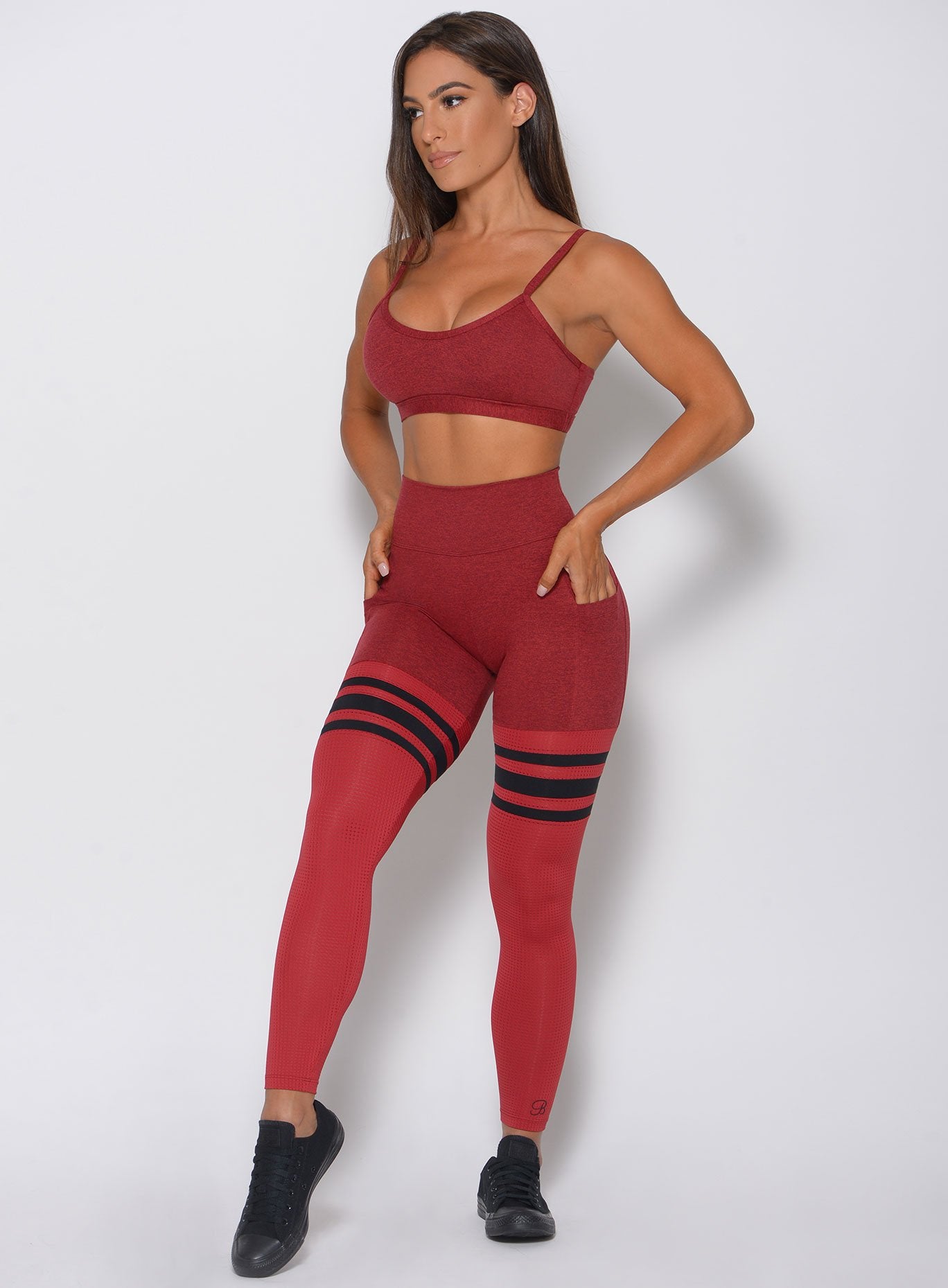 Model facing forward angled left wearing a red/maroon sports bra and matching high waist leggings