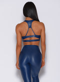 Back profile view of a model in our power gloss bra in navy and a matching leggings 