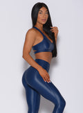 Right side profile view of a model in our power gloss bra in navy and a matching leggings