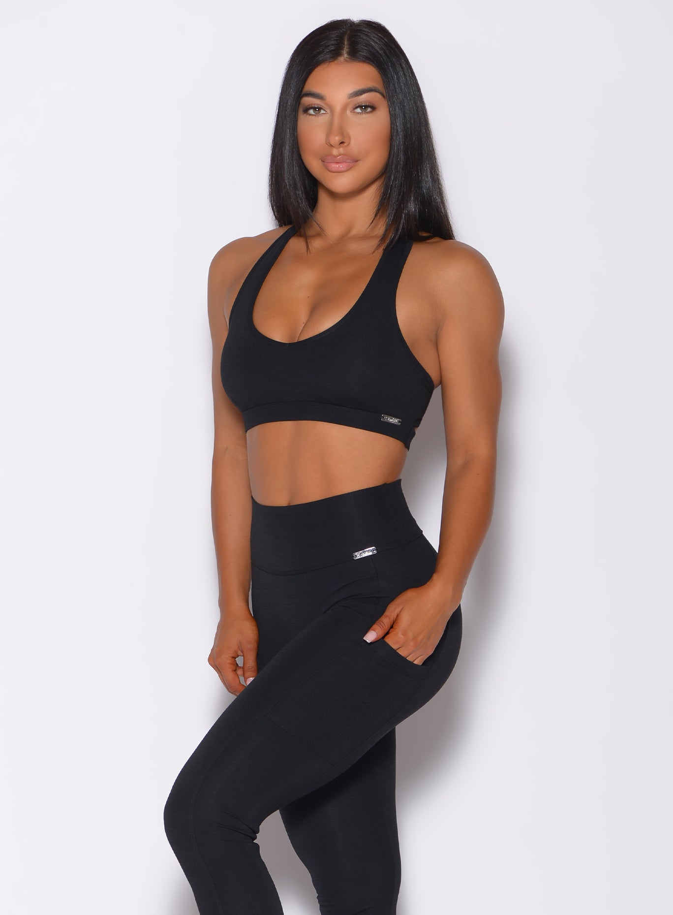 Front profile view of a model in our black power rib sports bra and a matching hight waist leggings