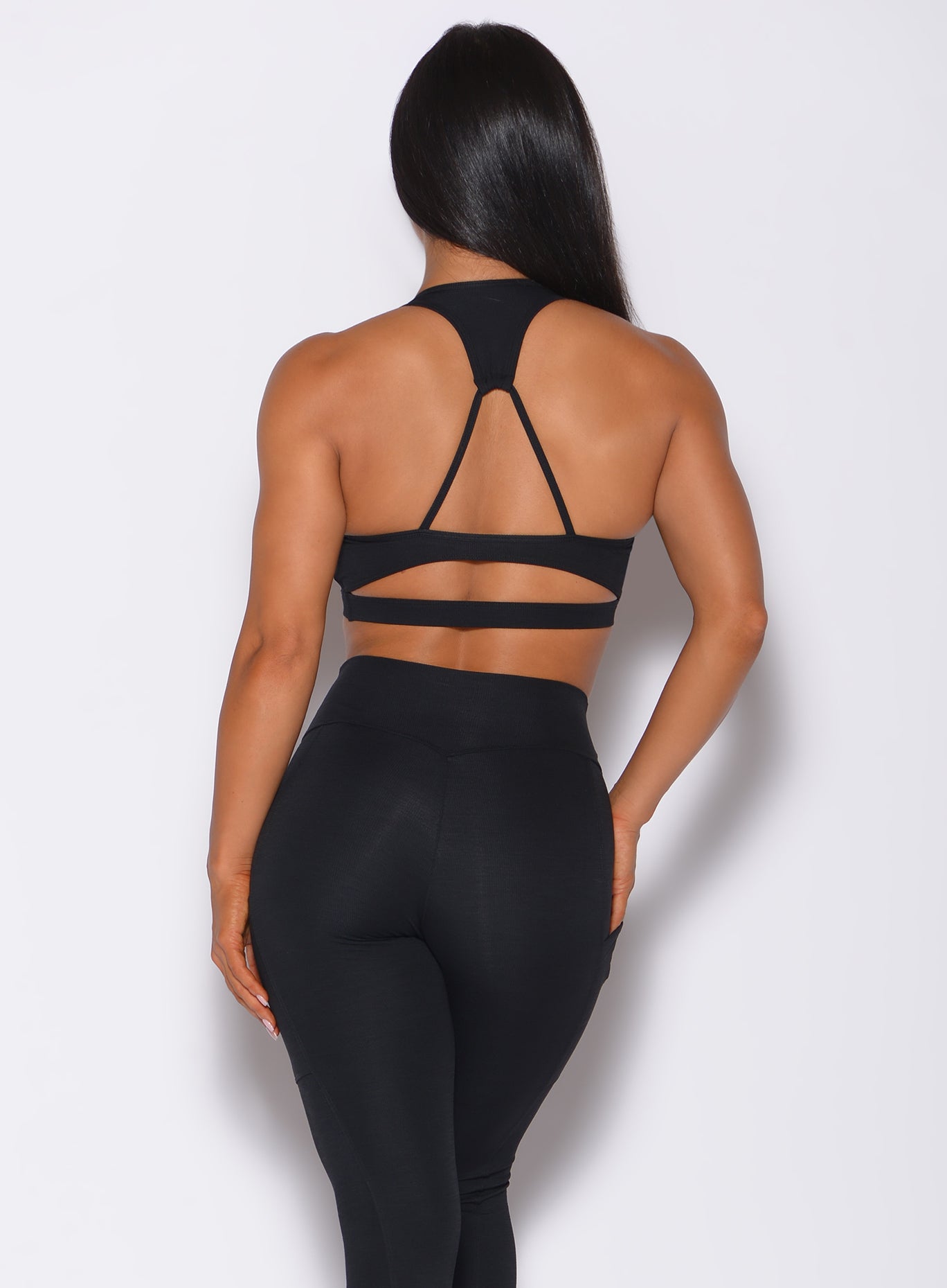 Back profile view of a model in our black power rib sports bra and a matching leggings
