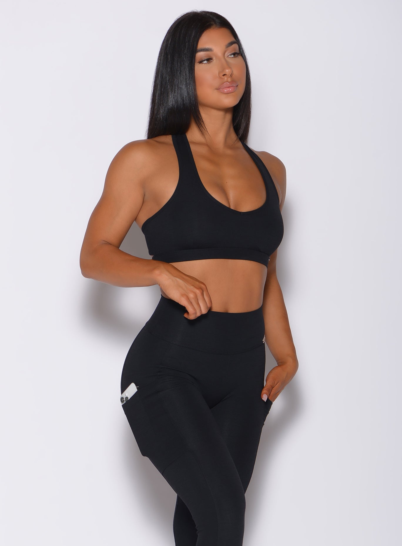 Right side profile view of a model angled right wearing our black power rib sports bra and a matching high waist  leggings