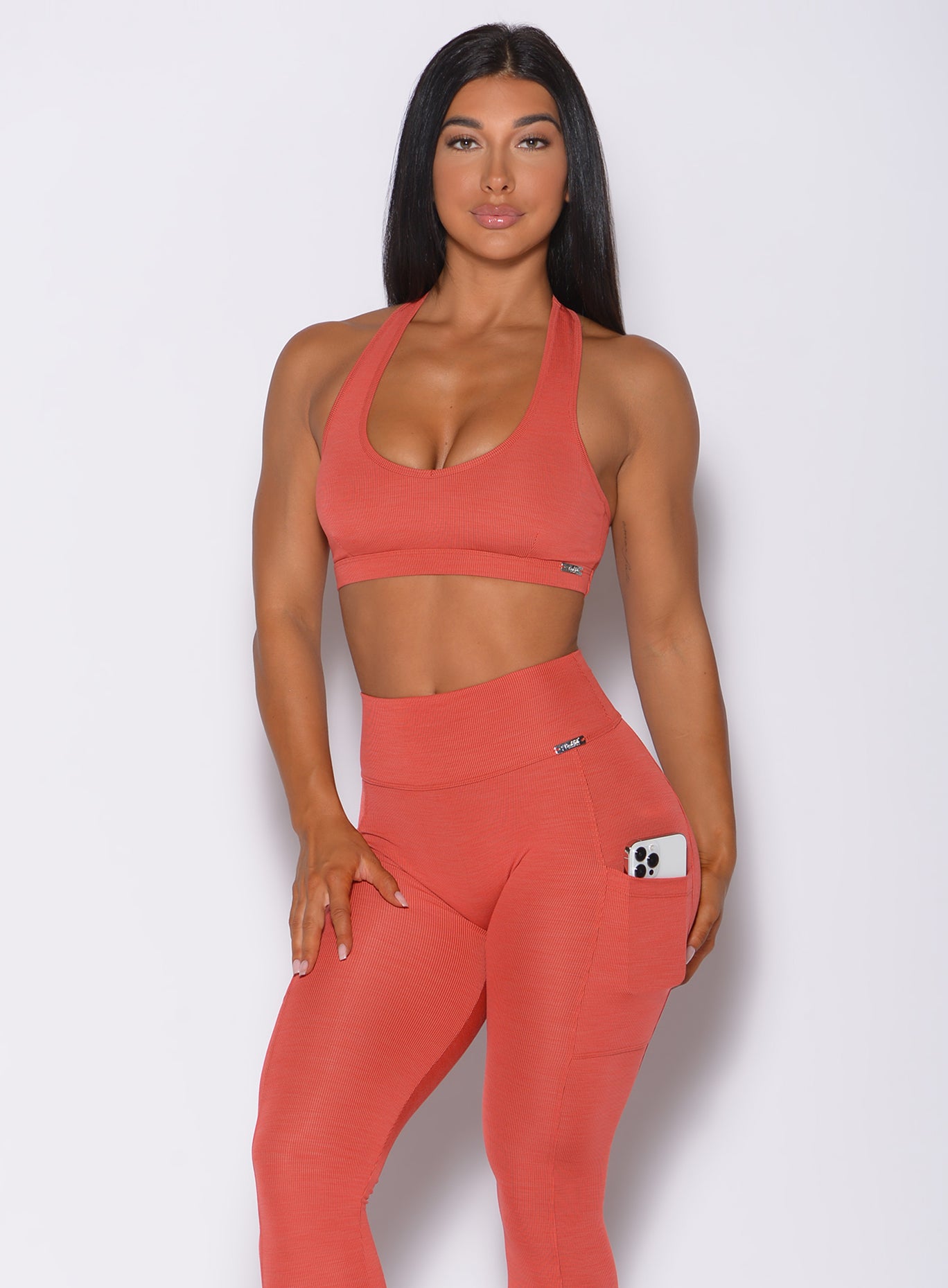 Model facing forward wearing our power rib sports bra in burnt orange color and a matching leggings