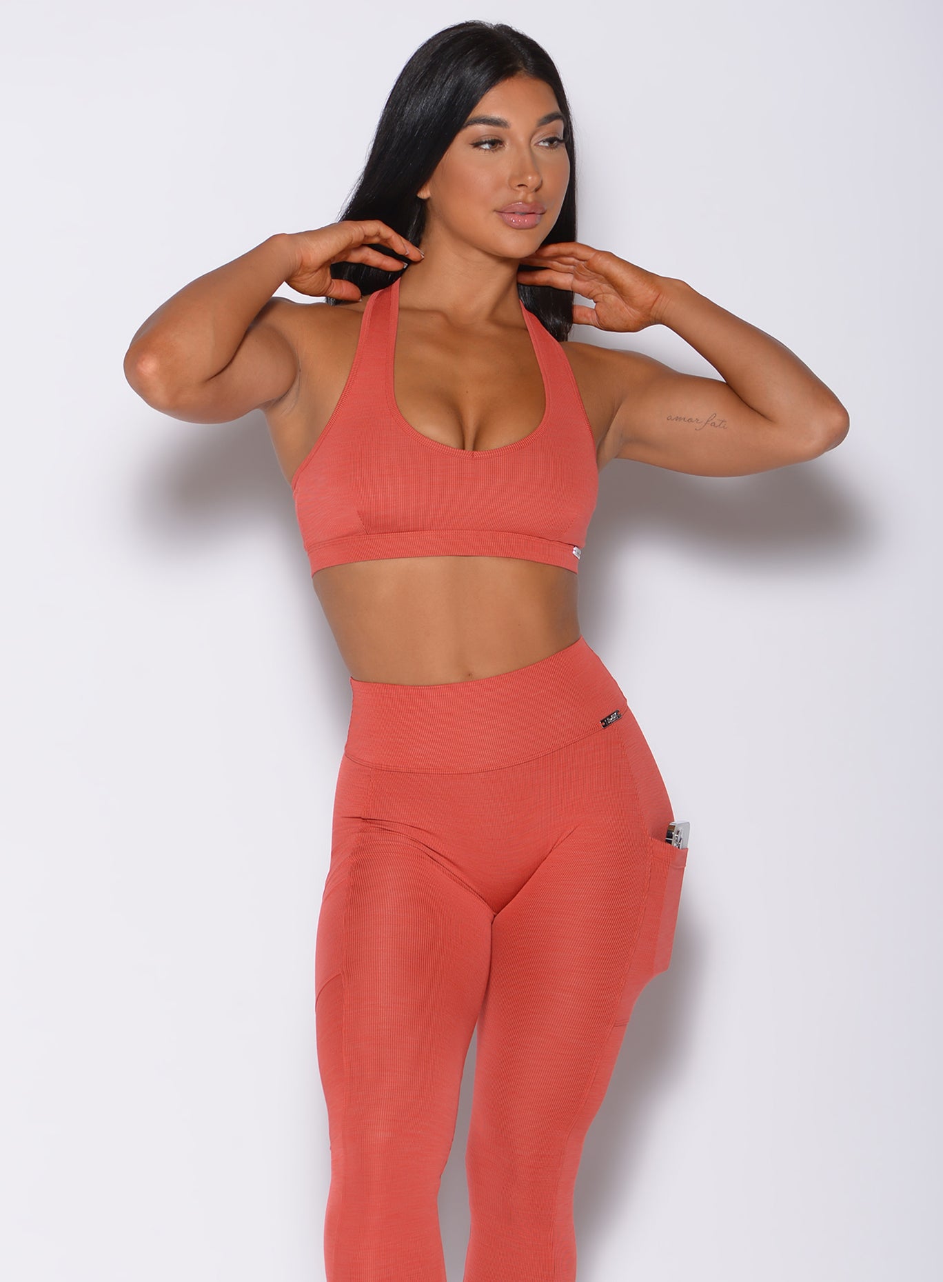 Front profile view of a model wearing our power rib sports bra in burnt orange color and a matching leggings