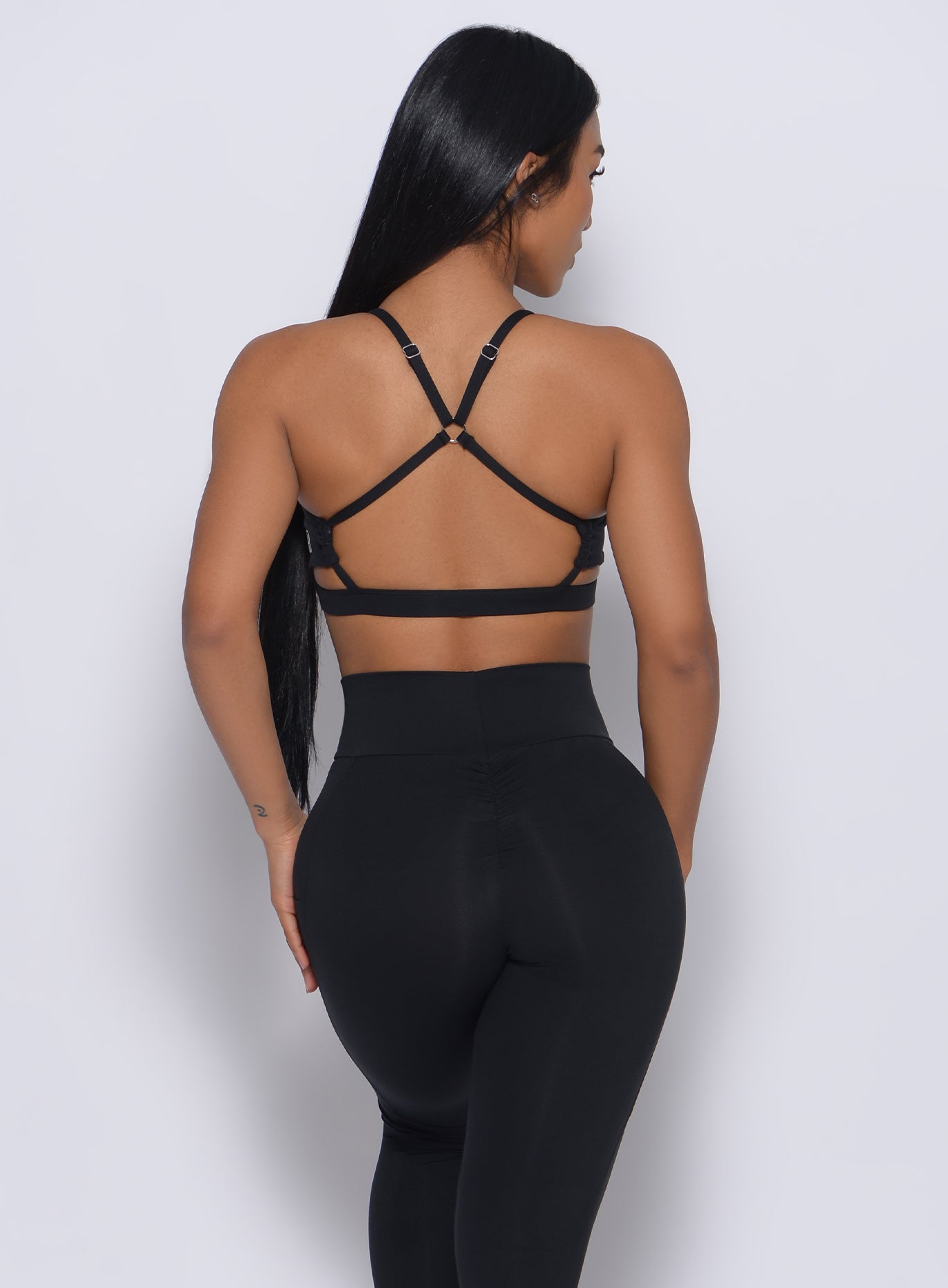 Back profile view of a model in our black pumped sports bra and a matching leggings