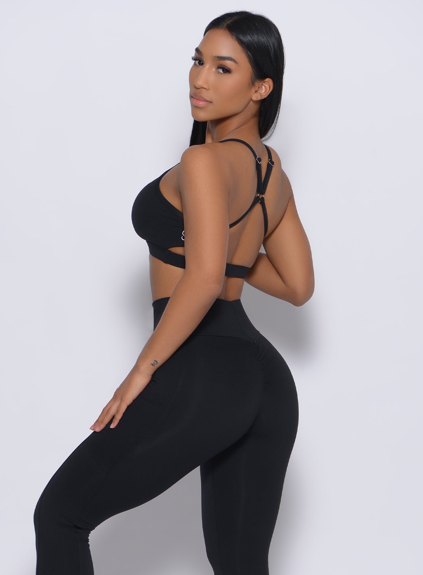Left side profile view of a model in our black pumped sports bra and a matching leggings