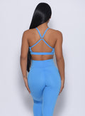 Back profile view of a model in our pumped sports bra in blazing blue color and a matching leggings