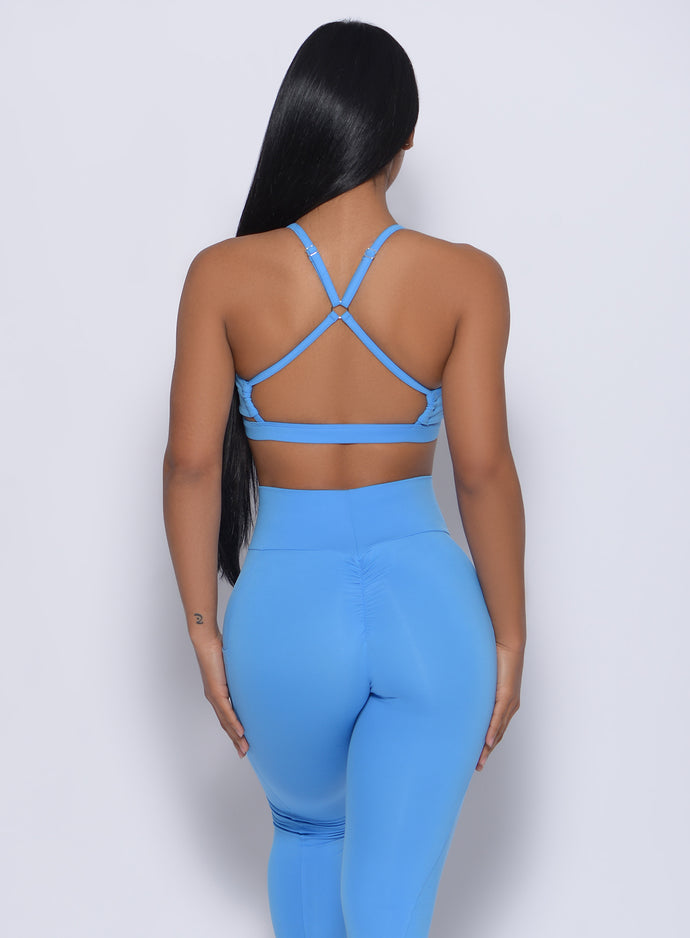 Back profile view of a model in our pumped sports bra in blazing blue color and a matching leggings
