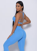 Right side profile view of a model in our pumped sports bra in blazing blue color and a matching leggings