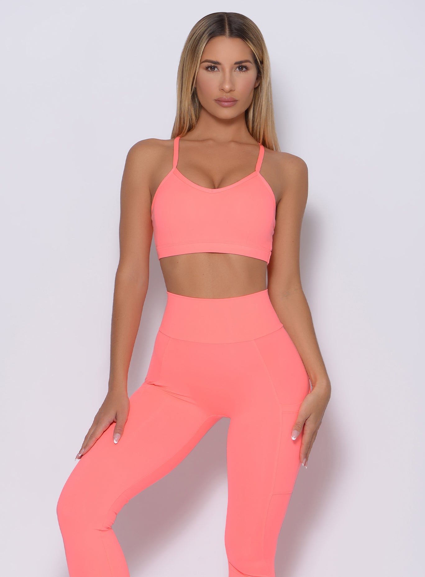 Front profile view of a model in our pumped sports bra in wild peach color and a matching leggings