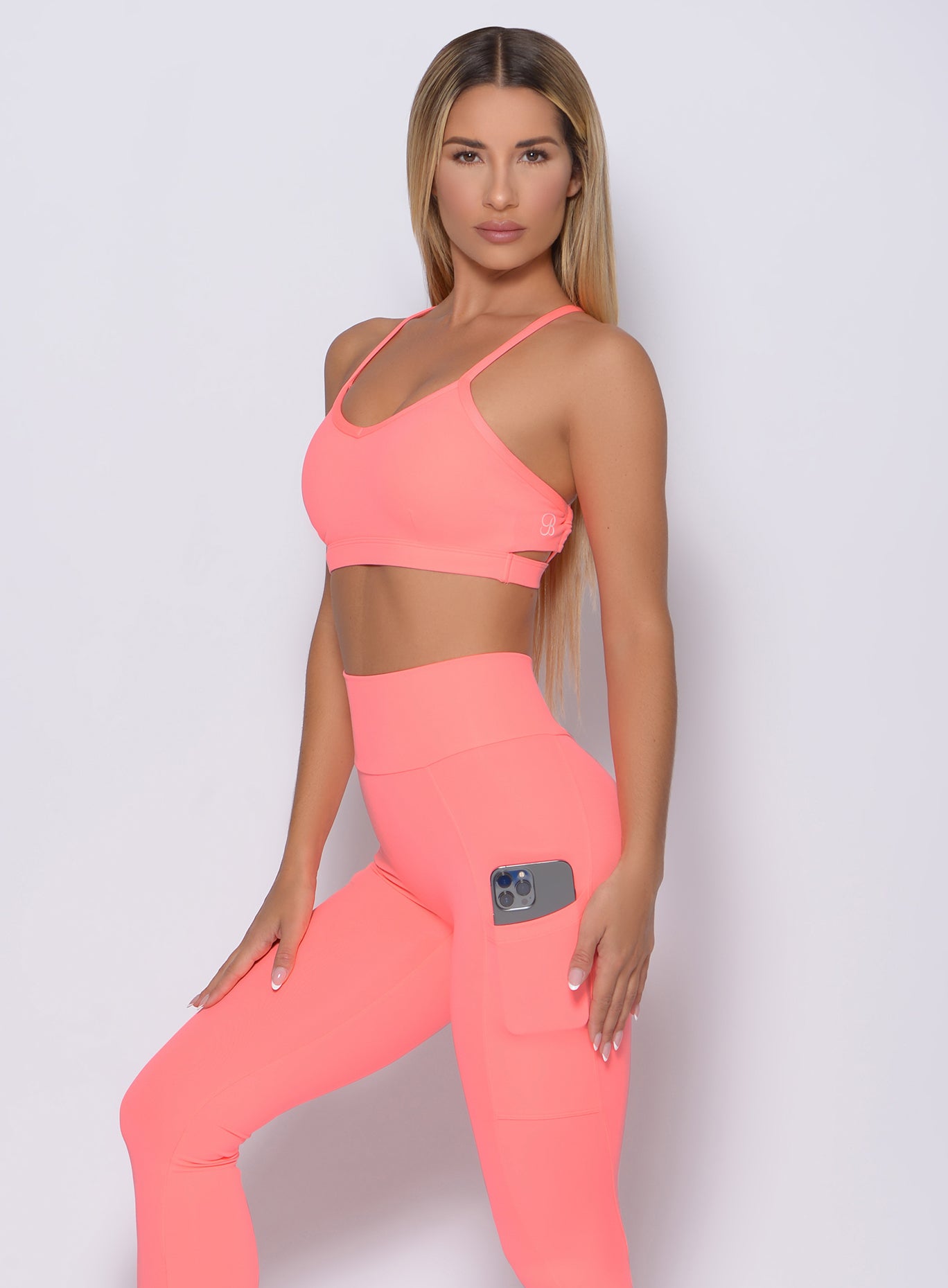 Left side view of the model wearing our pumped sports bra in wild peach color and a matching leggings